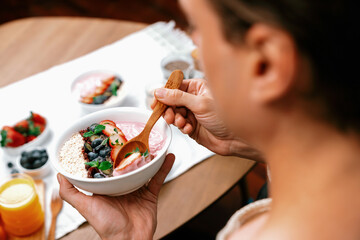 Focused photo on healthy food yogurt toppings with berry fruit in smart broadcaster tasting blurred face, promoting with advertisement online for benefit of vitamin and fiber each meal. Pecuniary.