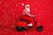 © deagreez - Full length profile photo of grandfather grey beard drive retro scooter look camera wear santa claus x-mas costume suspenders sunglass striped shirt cap isolated red color background