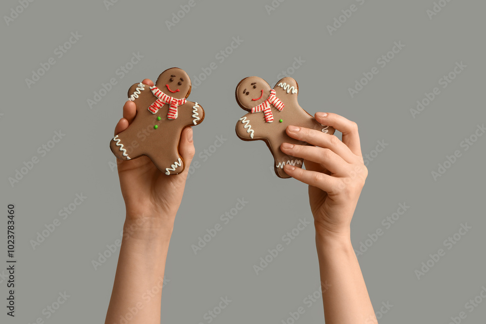 Female hands with Christmas sweet gingerbread cookies on grey background