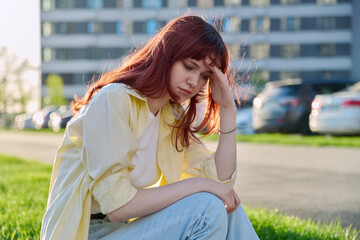 Wall Mural - Upset sad unhappy young female sitting outdoor