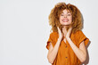 © SHOTPRIME STUDIO - Happy young woman with curly hair smiling and touching her face, wearing a brown shirt against a light background, showcasing a joyful and carefree expression