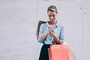 Wall Mural - happy female using mobile phone for sending text messages in social network sharing info about sales