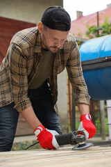 Sticker - Man polishing wooden planks with angle grinder outdoors