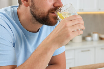 Wall Mural - Man drinking water with lemon indoors, closeup