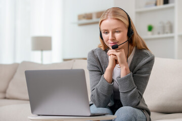 Wall Mural - Interpreter in headset having video chat via laptop on sofa at home