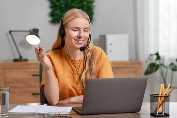 Wall Mural - Interpreter in headset having video chat via laptop at table indoors