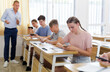 © JackF - Teenager students sitting in class room and using their smartphones.