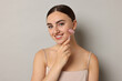 © New Africa - Beautiful young woman doing facial massage with roller on grey background