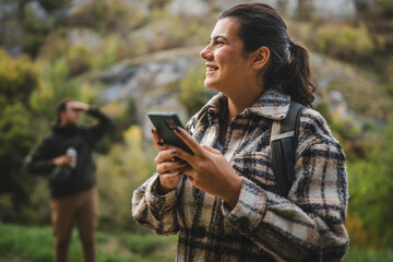 Adult woman hiker look for path and directions on mobile phone