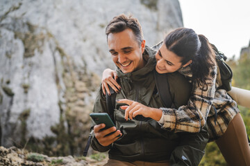 Girlfriend hug boyfriend while he use mobile phone on hiking