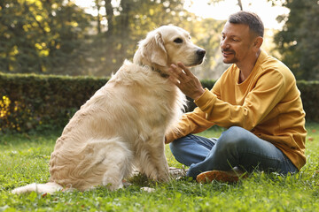 Wall Mural - Smiling man with cute Golden Retriever dog on spring day