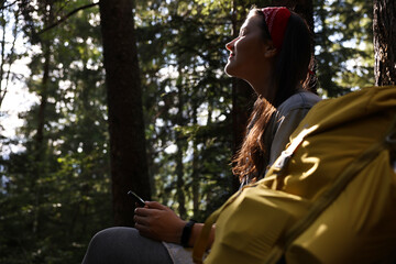 Canvas Print - Young hiker with smartphone in forest, low angle view