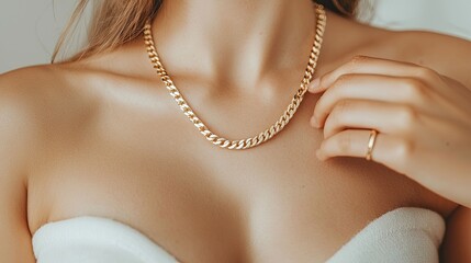 A close-up of a woman wearing a gold chain necklace, highlighting her shoulder and neckline, with elegant jewelry in focus.