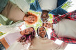 © Jose Calsina - Low angle view of a group of multiracial happy young teenagers hugging each others in a circle, looking down at camera with smiling faces, representing friendship, diversity, and togetherness outdoors