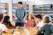 © JackF - Schoolboy preparing for lesson with his friends discussing literature together in school library indoor