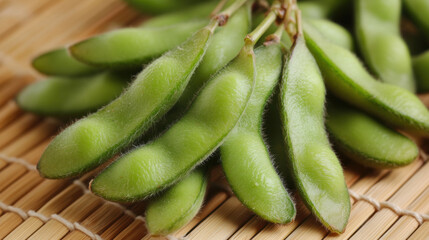 Close up of fresh edamame pods resting on bamboo mat, showcasing their vibrant green color and smooth texture. These nutritious beans are often enjoyed as healthy snack or appetizer