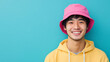 © Keitma - Young asian man wearing a pink bucket hat isolated on a blue background with copy space