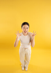 full body image of young asian girl posing on yellow background