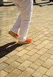 © sirbouman - Close-up of feet wearing the typical Catalan folk footwear, espardenyes, dancing the steps of the Catalan dance, the sardana, on a cobblestone floor illuminated by sunlight.