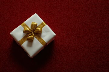 Elegant gift with gold ribbon on red background