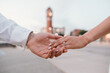 © Cavan Images - Bride and groom holding hands, blurred clock tower in the background