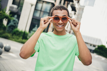 Poster - Portrait of nice young man hands touch sunglass wear t-shirt weekend walk downtown street outdoors