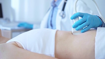 Wall Mural - Doctor man wearing a blue medical gloves using an ultrasound equipment on a female patient lying down in clinic cabinet, close up view. Medicine concept