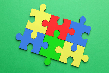 Sticker - Many colorful puzzle pieces on green background, top view. Symbol of autism