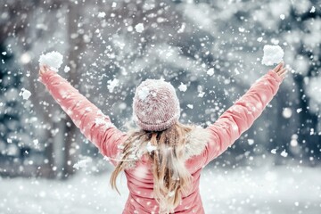 Canvas Print - An attractive woman enjoys winter in the middle of a snowy landscape, wearing warm clothes with hats and gloves and playing with snow in the middle of a snowy landscape. It is cold and Christmas-like