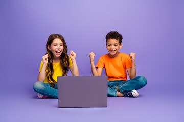 Poster - Full body photo of cute little boy girl winning netbook dressed stylish yellow orange clothes isolated on purple color background