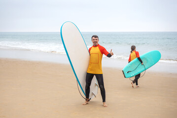 Family of surfers learning to surf in the Atlantic ocean. First surfing lesson. Amateur surfer. Surfing training. Photo for surfing school advertising on social media.