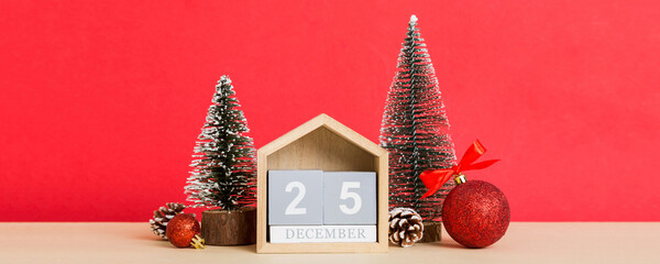 25 december. Christmas composition on colored background with a wooden calendar, with a gift box, toys, bauble copy space