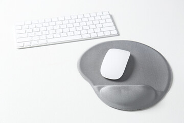 Sticker - Keyboard, mouse and mousepad with arm rest on white table. Space for text