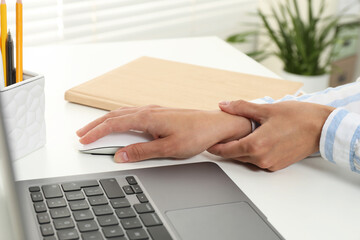 Wall Mural - Carpal tunnel syndrome. Woman suffering from pain in wrist at desk indoors, closeup