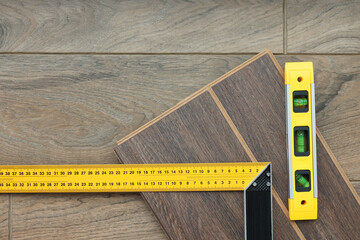 Sticker - Angle ruler, level tool and laminate flooring pieces on wooden surface, top view