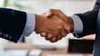 © fotofabrika - Business professionals engaged in a handshake, marking a successful partnership in a modern office setting during the daytime
