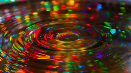 A stunning indoor shot captures a water droplet, its surface reflecting intricate patterns and light. The interplay of color and detail transforms simplicity into art.