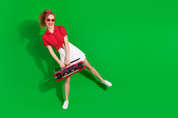 Sticker - Full size photo of pretty young girl sunglass hold boombox dancing wear trendy red retro outfit isolated on green color background