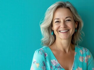 cheerful portrait of a middle-aged woman smiling against a vibrant turquoise background, radiating positivity and warmth, capturing the essence of joy and confidence