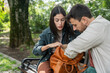 © Srdjan - Young couple sitting in the park searching for wallet in women bag. Man helping his girlfriend to find lost wallet or she is pickpocket victim