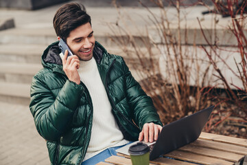 Wall Mural - Photo of attractive nice successful man sitting on cafe terrace speaking phone autumn day outdoors