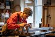 © DimaBerlin - Focused woodworker applies leather pads to bed legs in workshop, enhancing stability and protection. Male craftsman using traditional woodwork methods, handmade furniture, leather work with bed frame