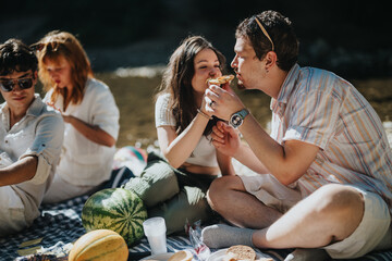 Sticker - A group of friends relaxes by a river, sharing snacks and smiles during a summer picnic. The atmosphere is filled with joy and companionship in the warm outdoor setting.