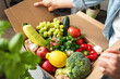 © Barillo_Images - Ripe farm grown fruits and vegetables in cardboard box. Woman unpacking her online order of organic and healthy vegetables.