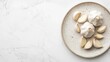 © ALIS ST - Garlic bulbs and peeled cloves on a plate, top view with a minimalist white background and plenty of copy space available