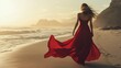 © fotofabrika - A woman in a flowing red dress walks along the beach during sunset, with waves gently lapping at the shore under a glowing sky