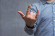 © vadish - Close-up of a man in a shirt shows hand gesture Rock'n'roll against a concrete wall.