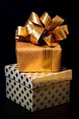 two gift golden boxes on a black background, closeup