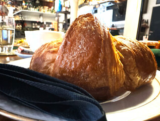 Close-up of fresh croissant on plate in cozy cafe setting