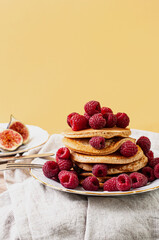 Delicious whole wheat healthy pancakes with raspberry, fork and knife styling natural light and copy space on the table with linen cloth background lifestyle